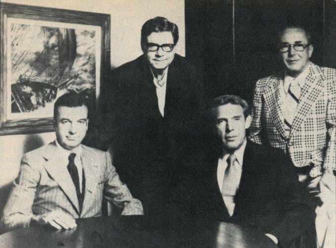 Black and white shot of Lummis, West, Gay and Rankin, all wearing a suit and tie. 