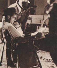 Howard Hughes reading in a chair on the set of The Outlaw. 