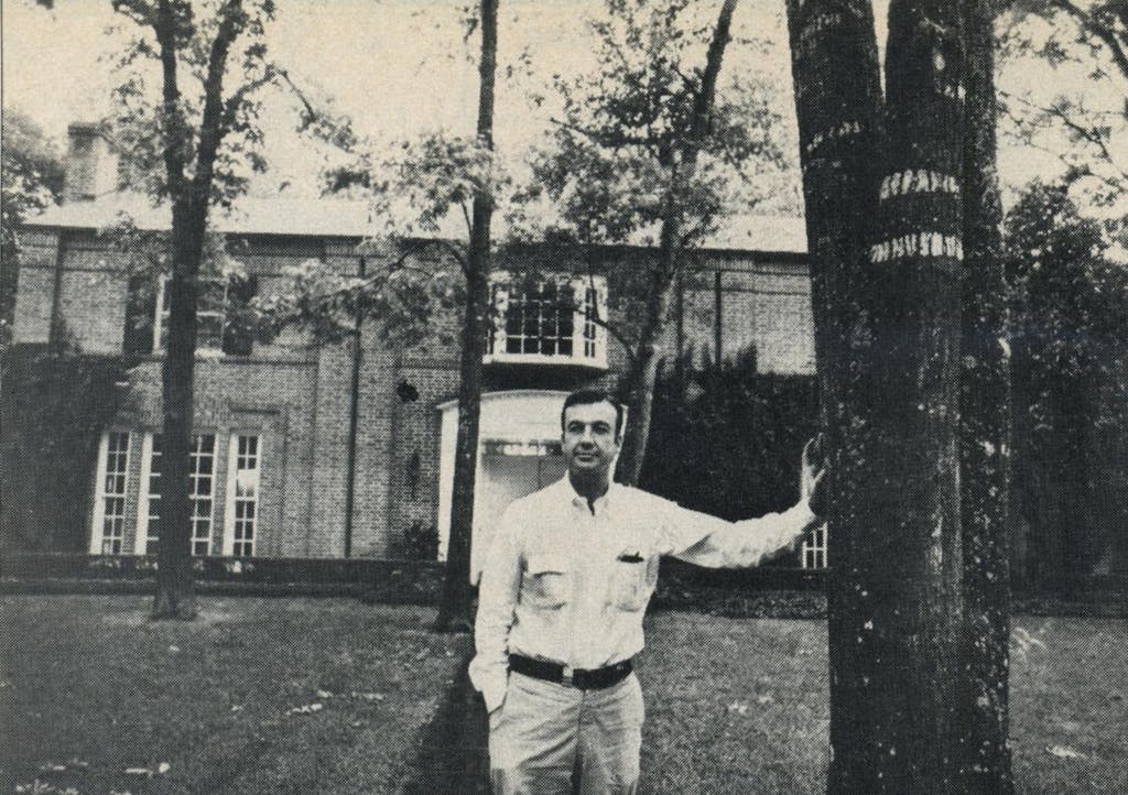 Lummis leans against a tree in front of his old home. 