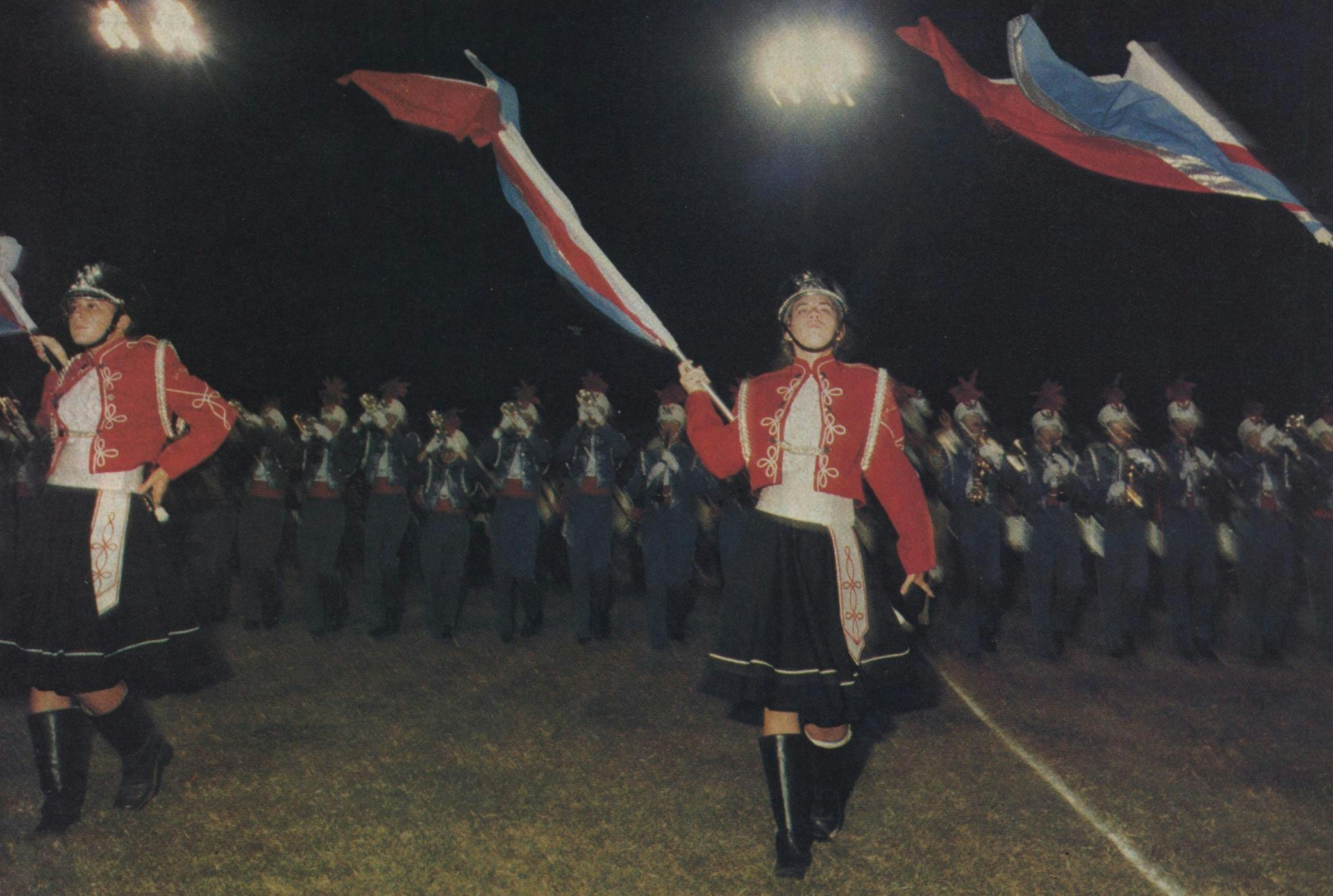 The flag bearers of neighboring Pearce High School strut arrogantly downfield. Note the asymmetry of their arms—bad form.