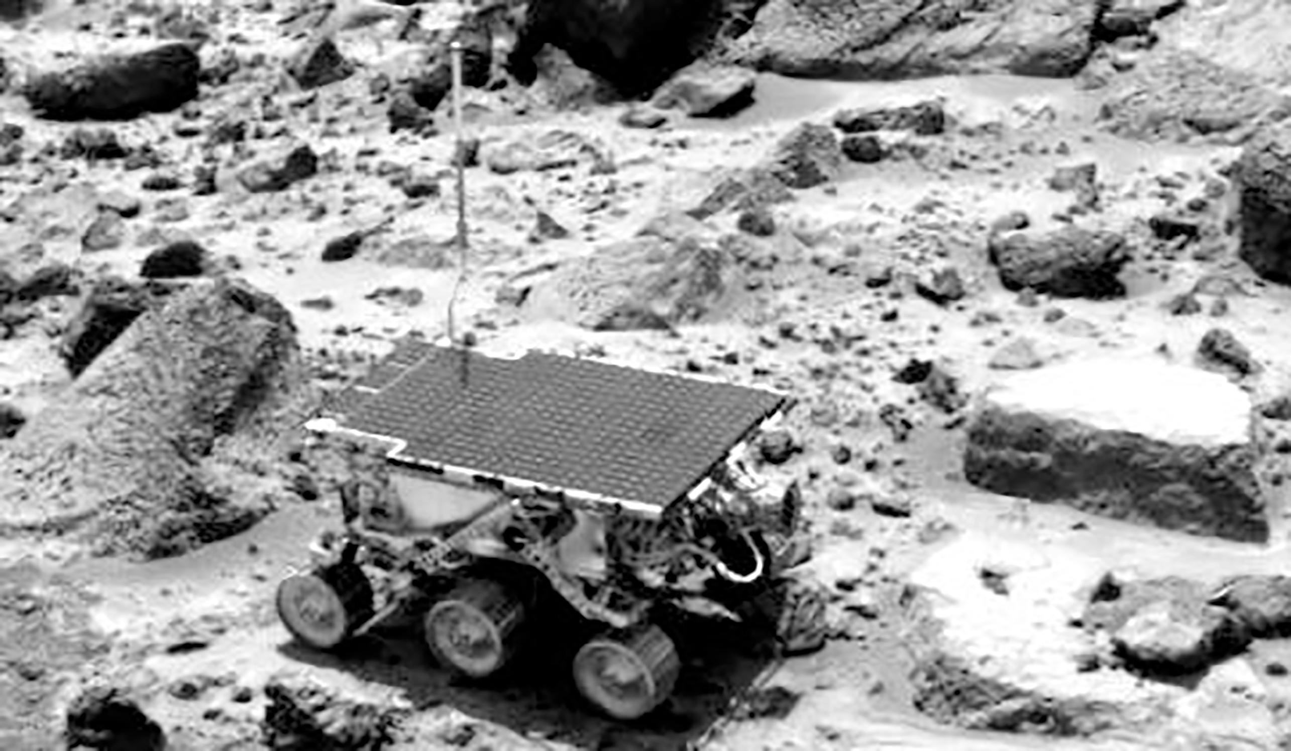 Closeup of the Sojourner Rover on the rocky, dirt ground of Mars. 
