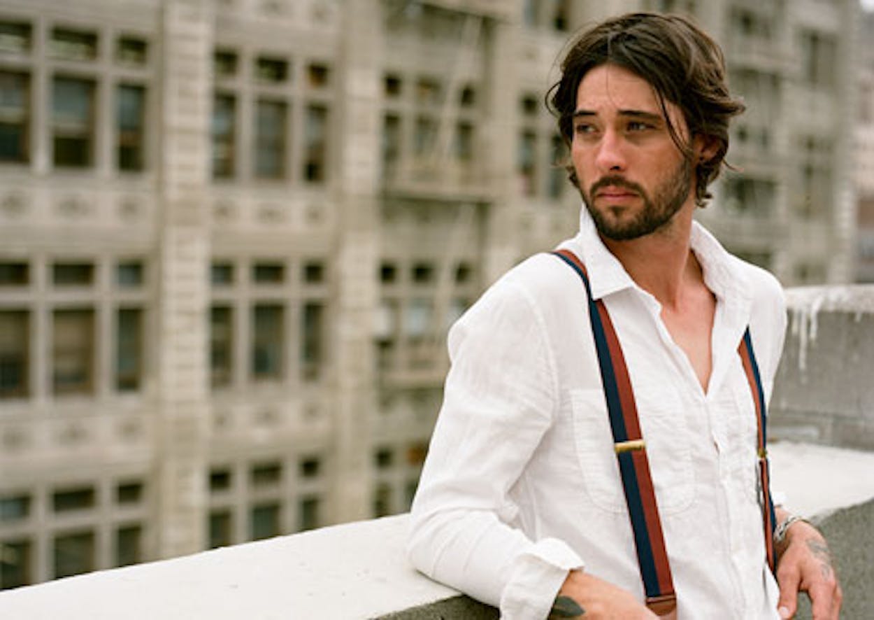 Ryan Bingham looks to his right and leans against a railing.