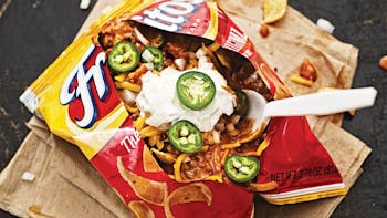 Frito pie topped with sour cream and fresh jalapeños.