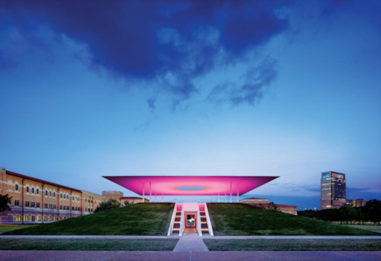 Landscape view of the Skyspace installation lit up bright pink.