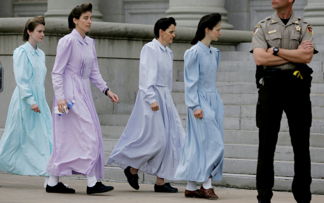 Female FLDS church members walk in front of the courthouse in their signature long, pastel dresses.