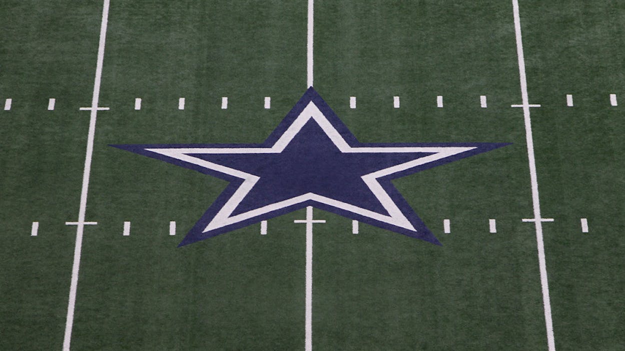 Dallas Cowboys logo on the football field.