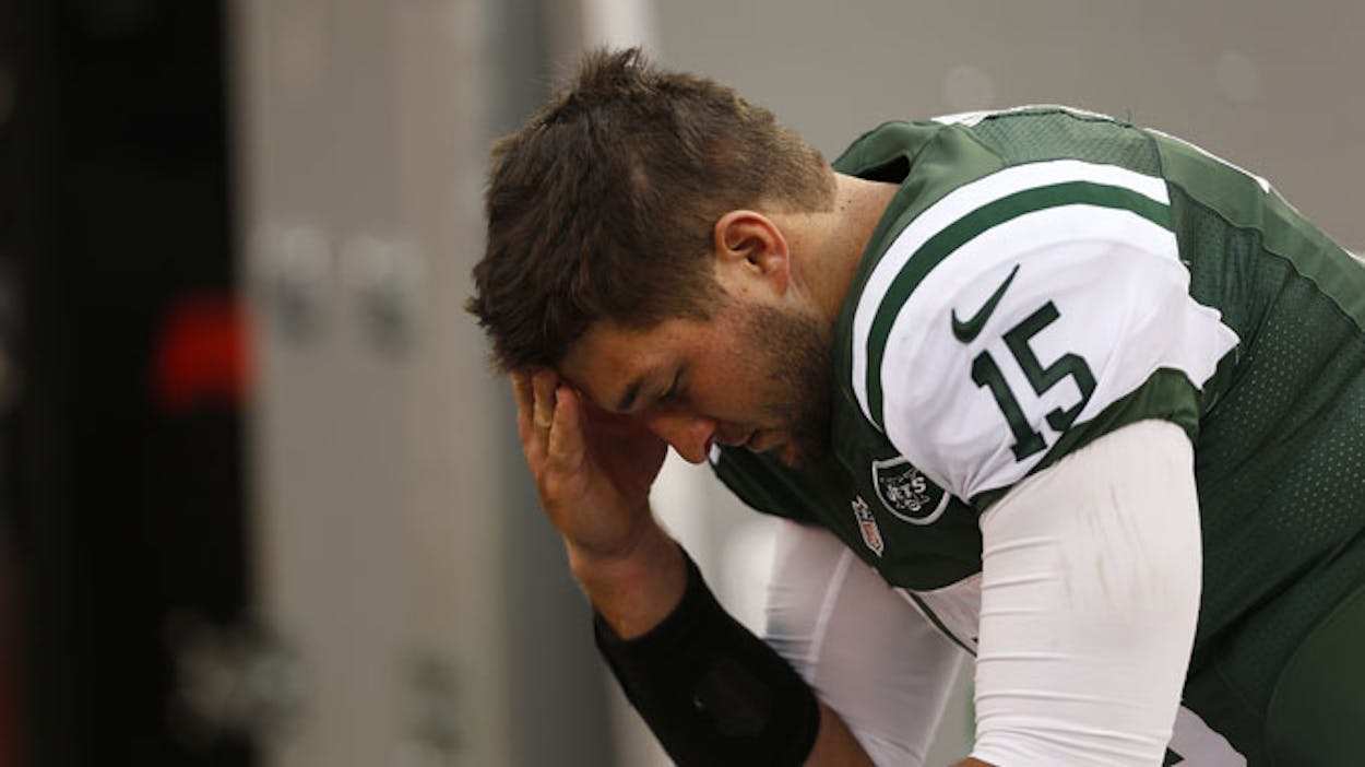 tim tebow with his head down in a locker room