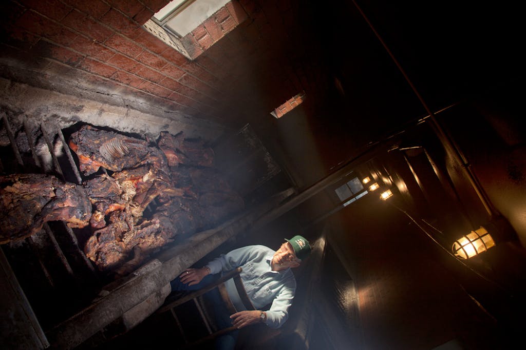 Wilbur Shirley checks pit full of whole hogs at Wilbur's in Gold