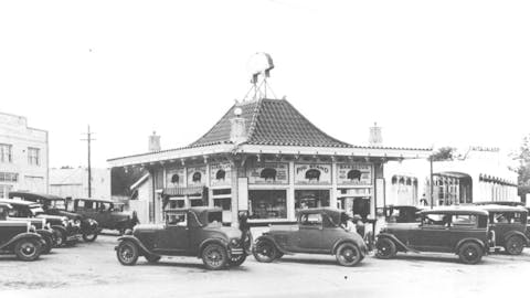 Black and white photo of old cars in front of the pig stand. 