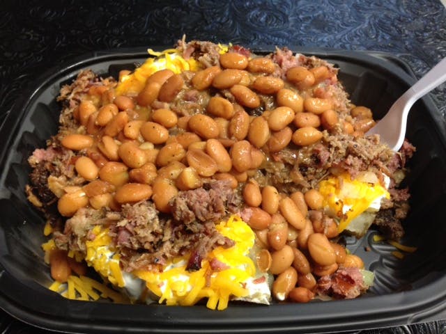 Baked potato hardly visible under a ile of brisket, cheese, beans, and sour cream. 