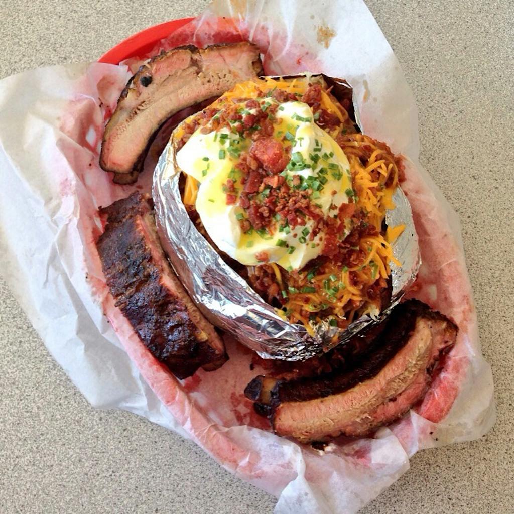 Stuffed baked potato surrounded by pork ribs. 