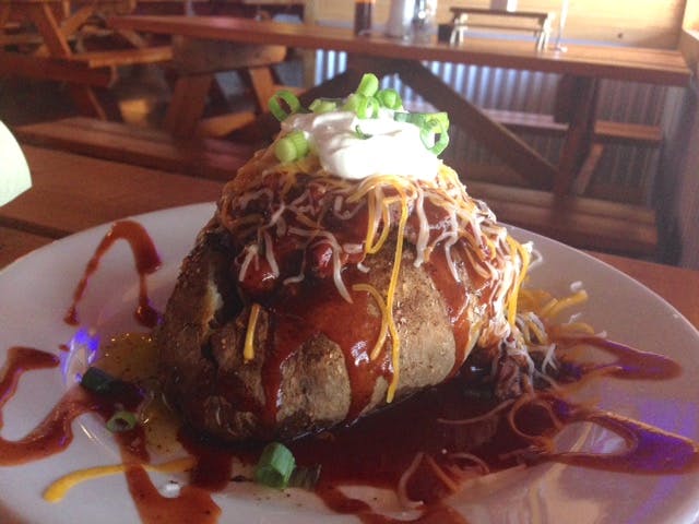 Stuffed baked potato, piled high with barbecue sauce, sour cream, cheese, and chives. 