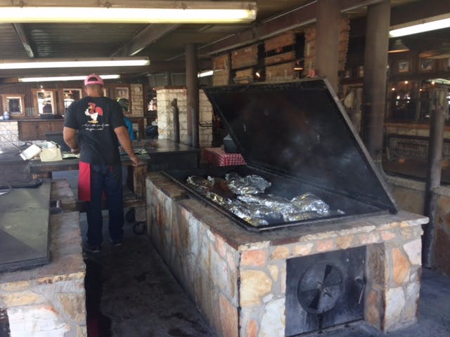 Tinfoil-wrapped brisket being cooked at Hard Eight BBQ. 