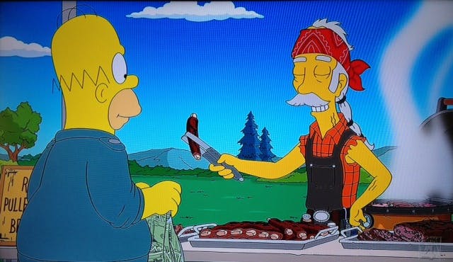 Homer Simpson being served a barbecued rib by a man in a cut-off flannel and a red bandana. 