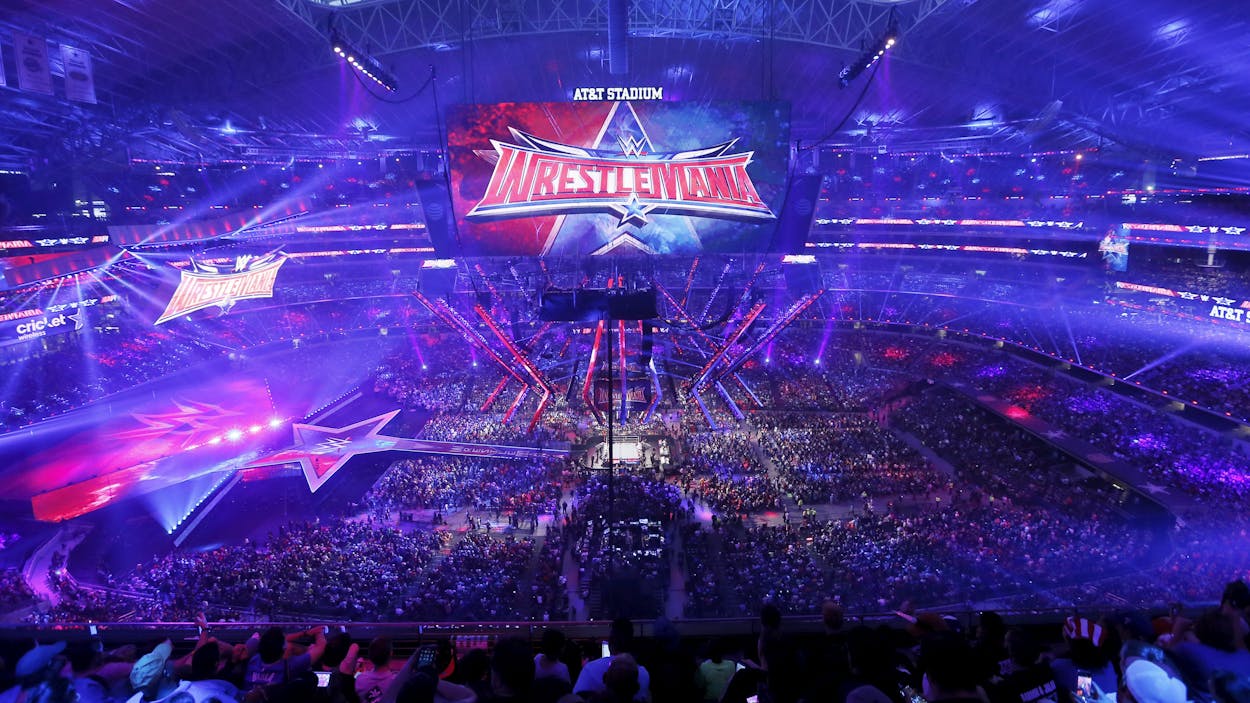 Aerial view of the Wrestlemania crowd and stage engulfed in blue and red lights.