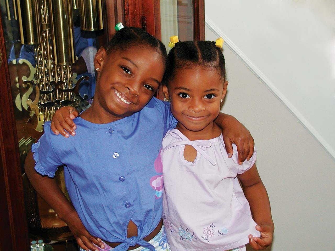 Six-year-old Simone Biles smiles with her arm around her sister. 