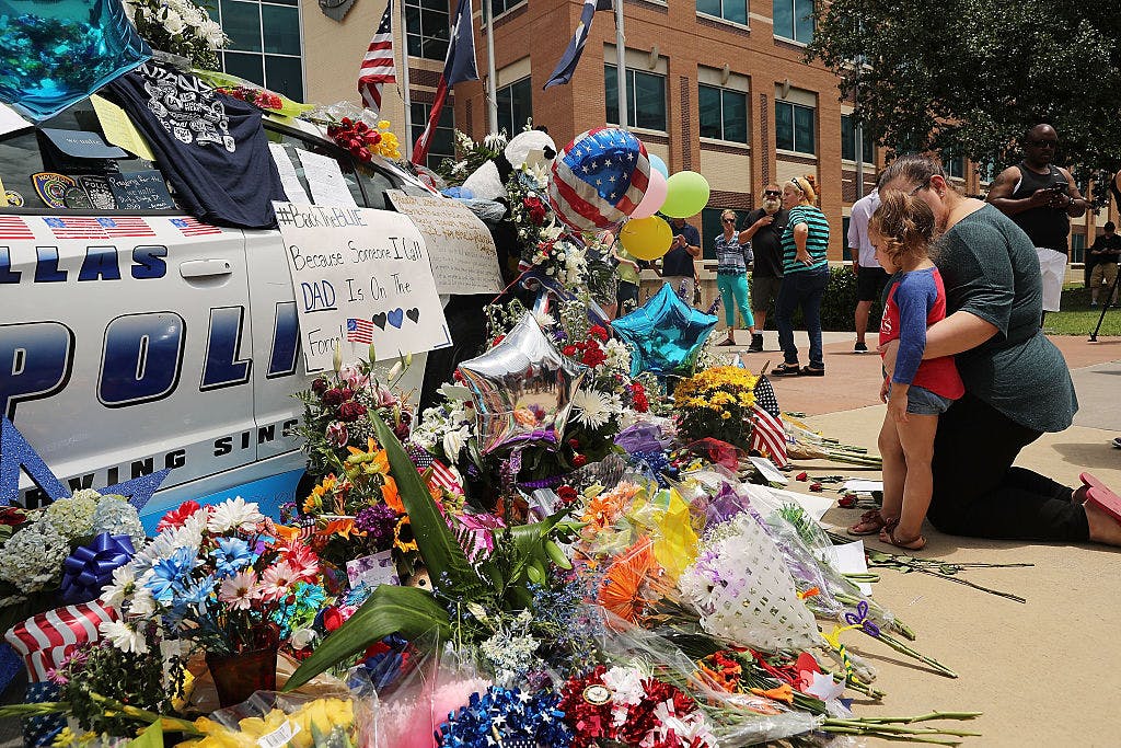 People visit a growing memorial at the Dallas police department's headquarters near the active crime scene in downtown Dallas following the deaths of five police officers on Thursday evening on July 9, 2016 in Dallas, Texas. 