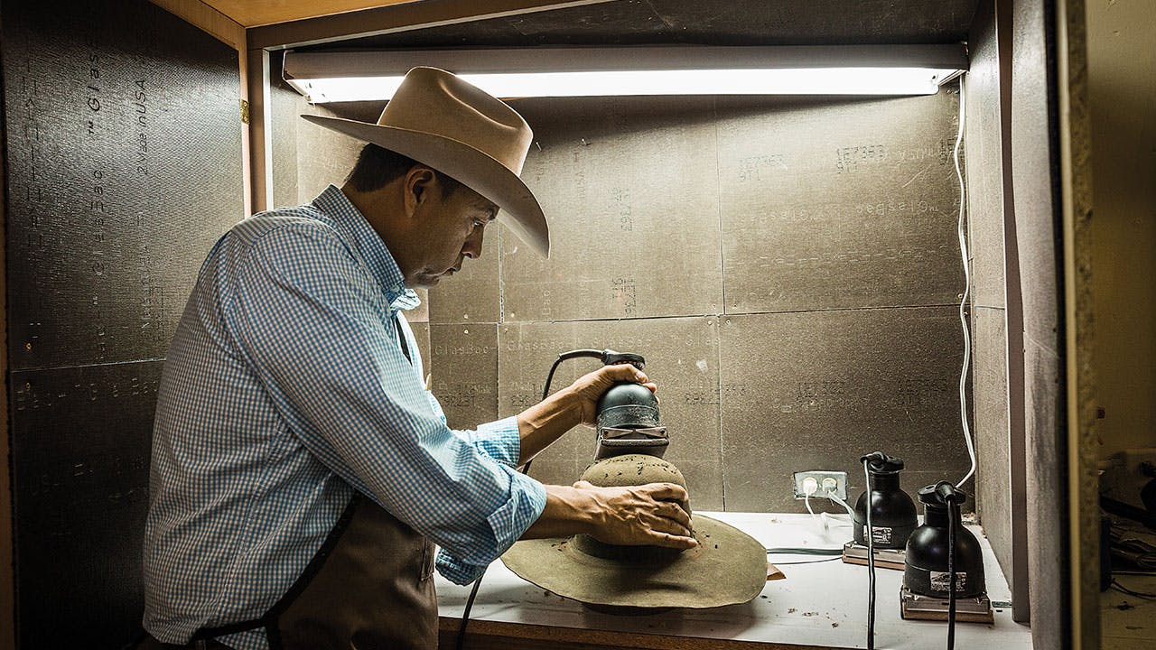 Funmaker sanding a hat to give it a more finished look.