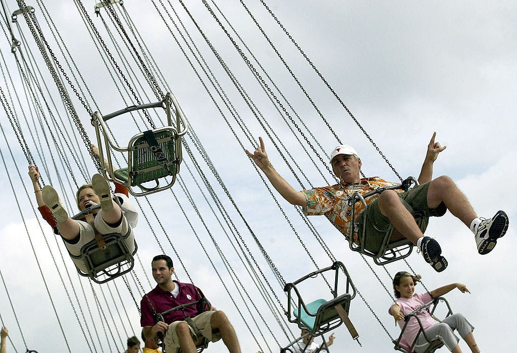 University of Texas fan, Larry Parks, gives the "hook em horns" sign while riding the swings before the game against the Oklahoma Sooners and the Texas Longhorns during the State Fair of Texas on October 11, 2003 in Dallas, Texas. 
