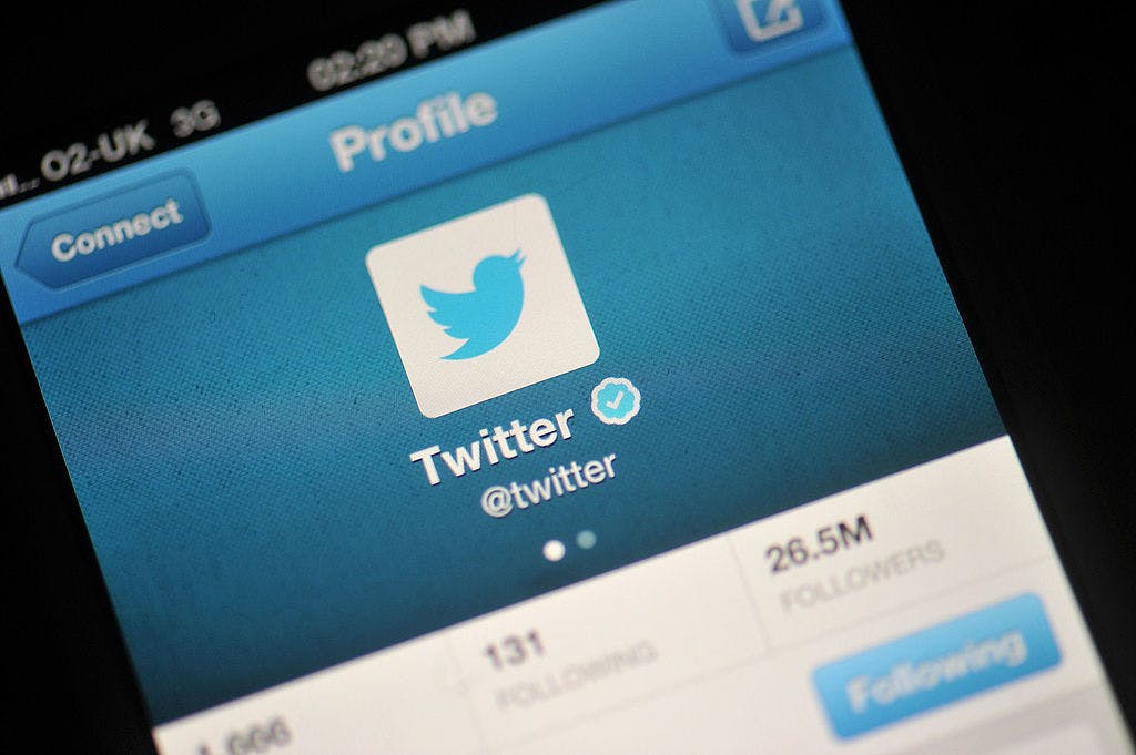 In this photo illustration, The Twitter logo is displayed on a mobile device.