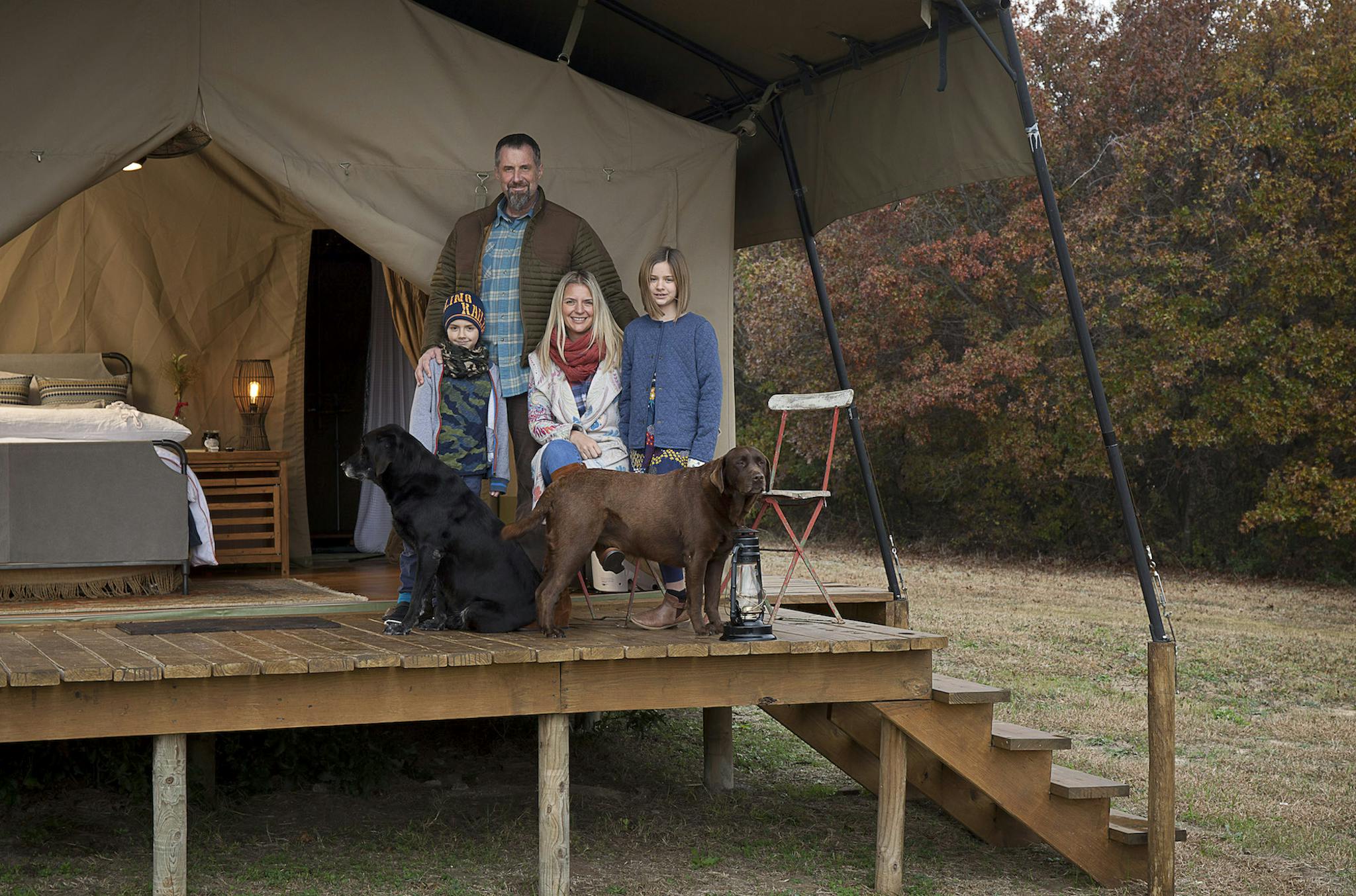 The Munson family on an elevated wooden deck outside of one of their tents.