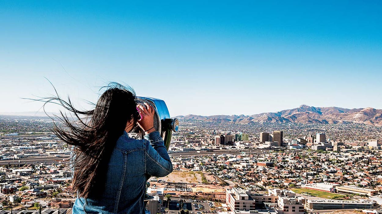 A woman looking at El Paso through an observation viewer.