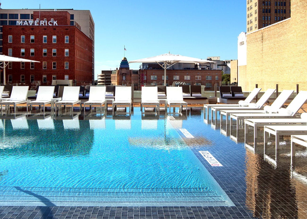 Clear, blue water reflects the lounge chairs at the St. Anthony Hotel rooftop pool. 