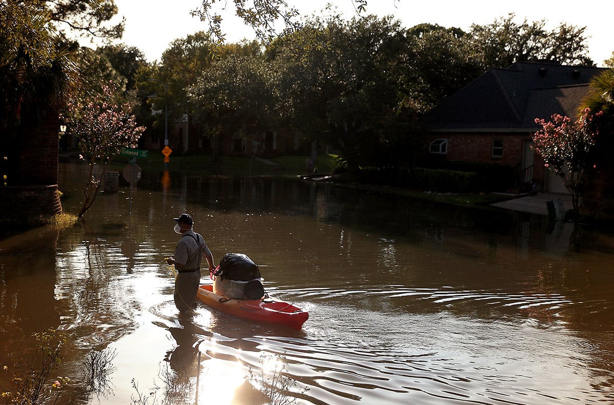 Houstonian wading through the flooded streets with a kayak. 