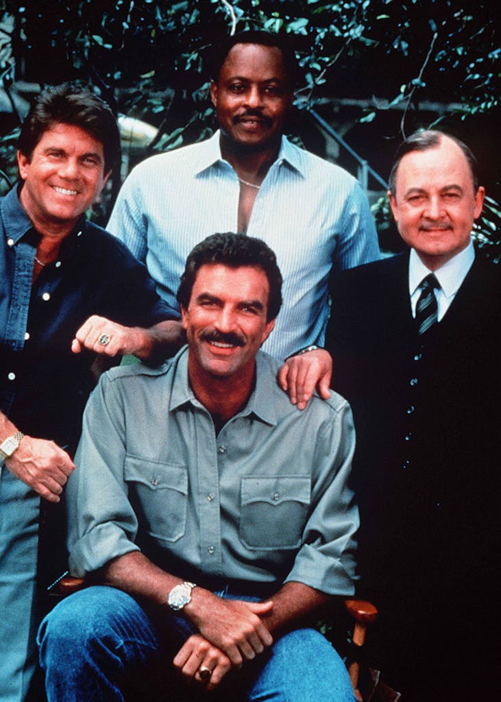 Cast members of Magnum P.I. smile and look at the camera. 