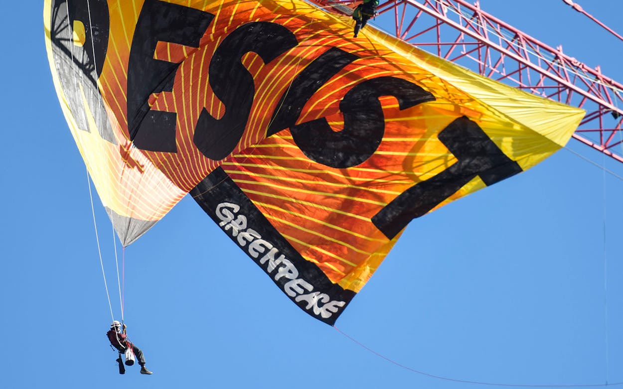 Greenpeace activists hang from a construction crane with a banner that reads 'Resist', in Washington, DC on January 24, 2017.
