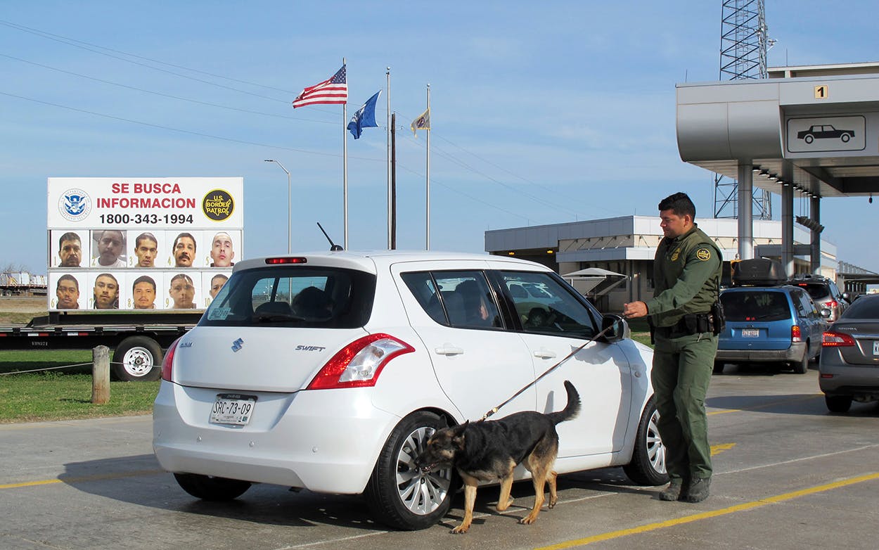 A Border Patrol agent uses a dog to inspect a car waiting to pass through the Laredo North vehicle checkpoint in Laredo on Friday, February 2, 2018.
