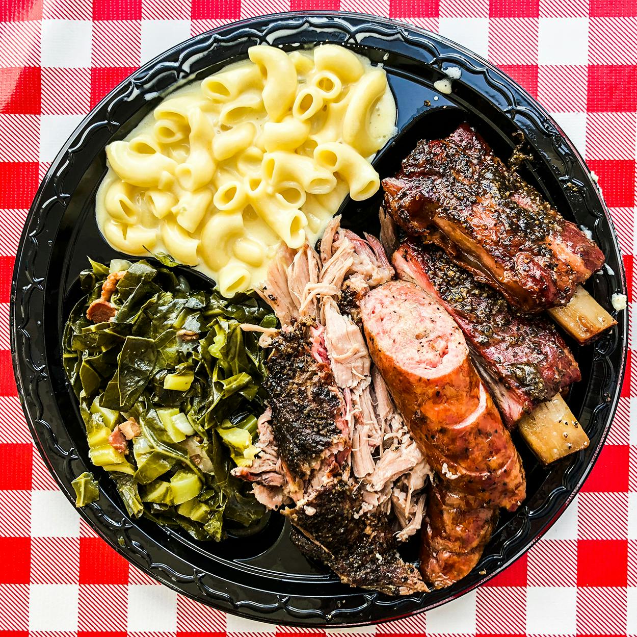 Collard greens with bacon and creamy mac and cheese served alongside pork shoulder, sausage and pork ribs from LJ’s BBQ in Brenham.