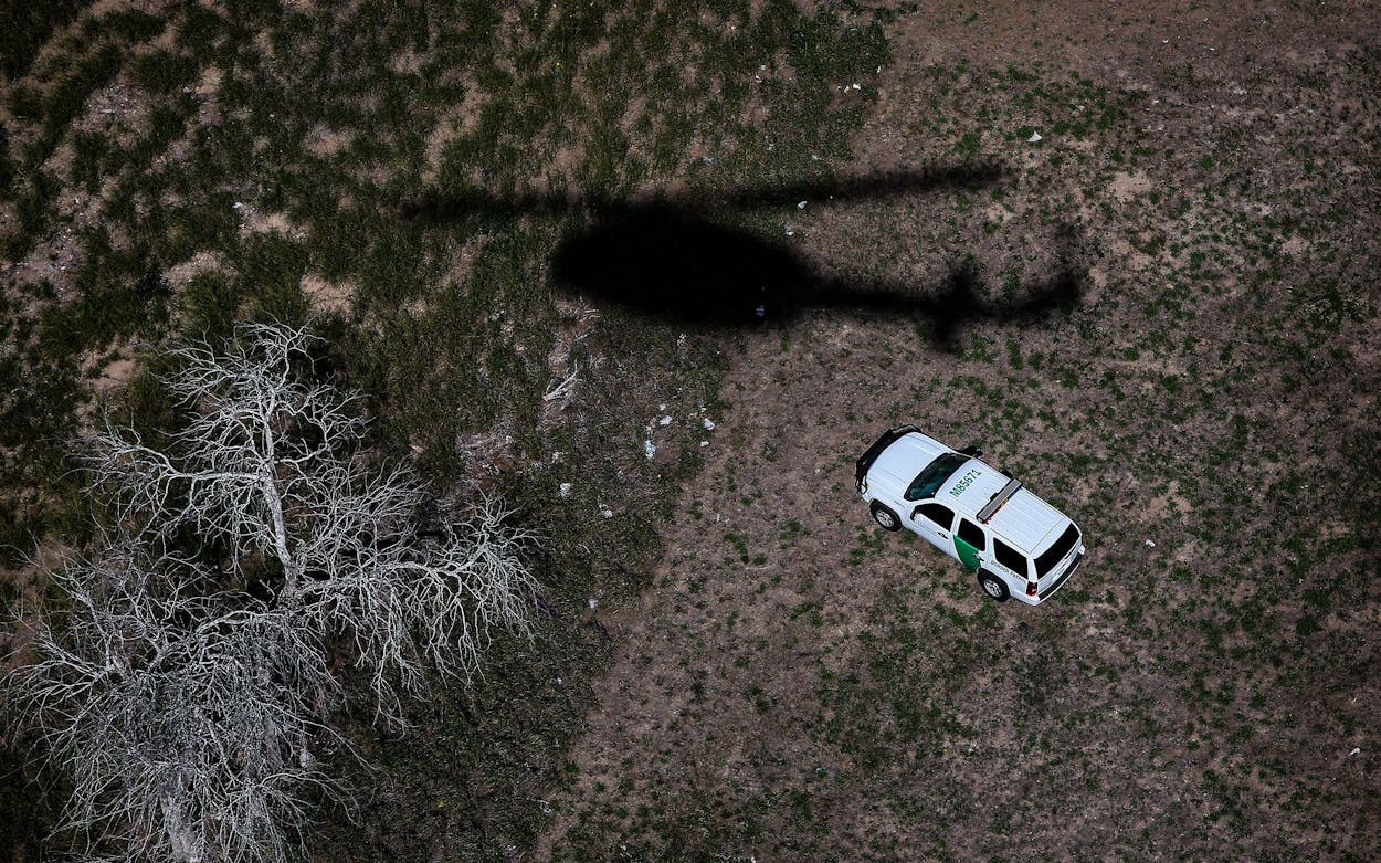 The shadow of a helicopter from U.S. Office of Air and Marine passes a U.S. Border Patrol vehicle as agents search for undocumented immigrants on September 11, 2014 in Falfurrias, Texas.