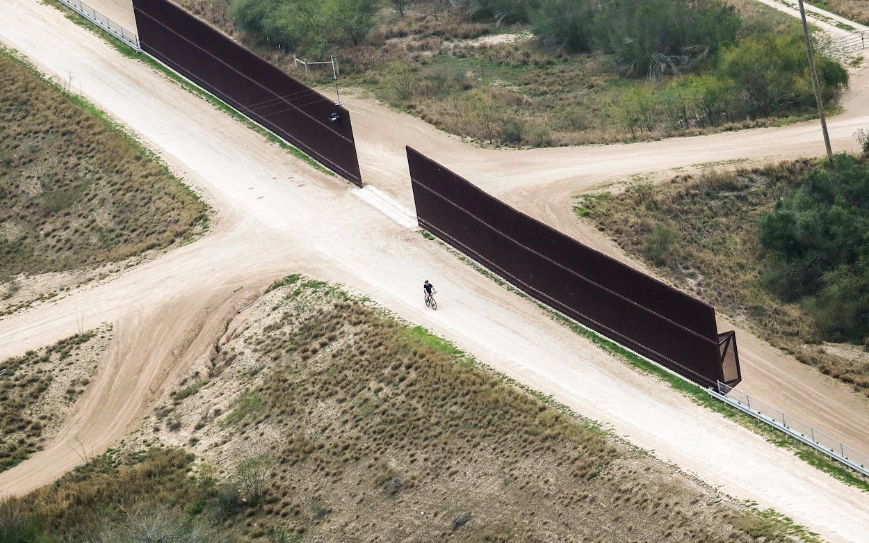 A cyclist rides along a portion of the U.S.-Mexico border fence on February 21, 2018 in McAllen.