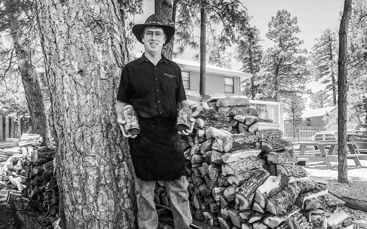 James Jackson stands next to a pile of Lockhart post oak wood.