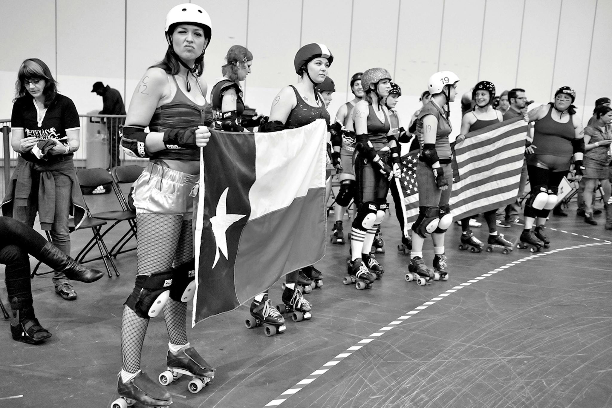 Members of the Texas Rollergirls hold Texas and American flags at a tournament in London