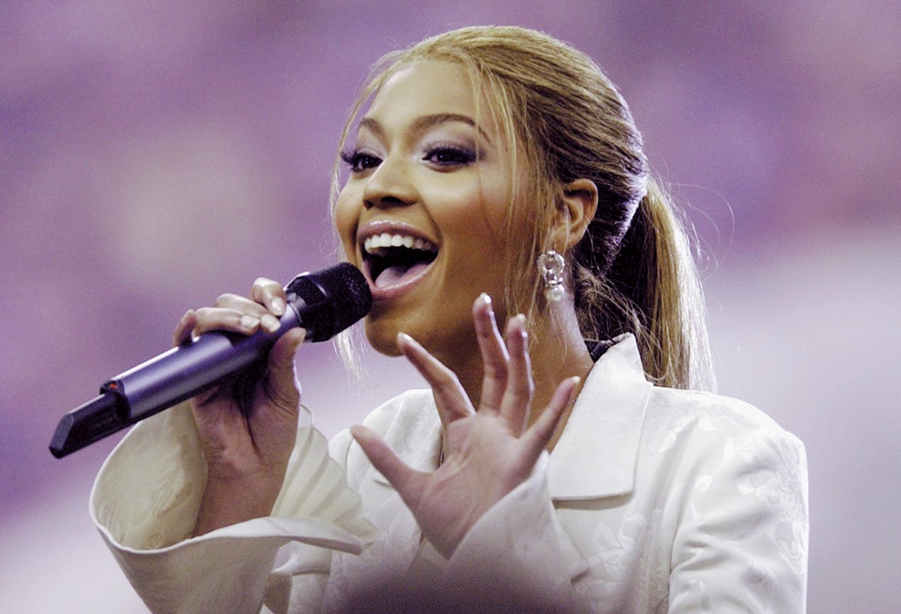 Beyonce smiling as she sings at the superbowl. 