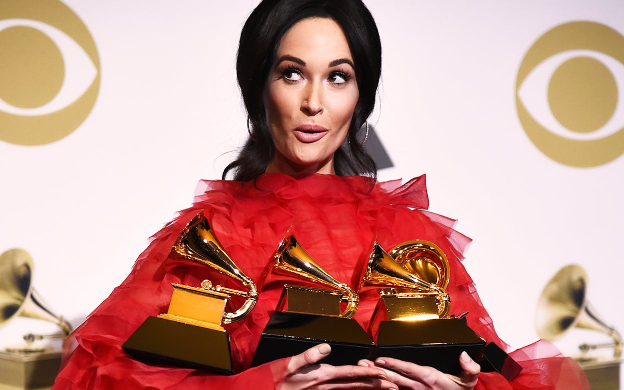 Kacey Musgraves poses in red frills with her three grammy awards.