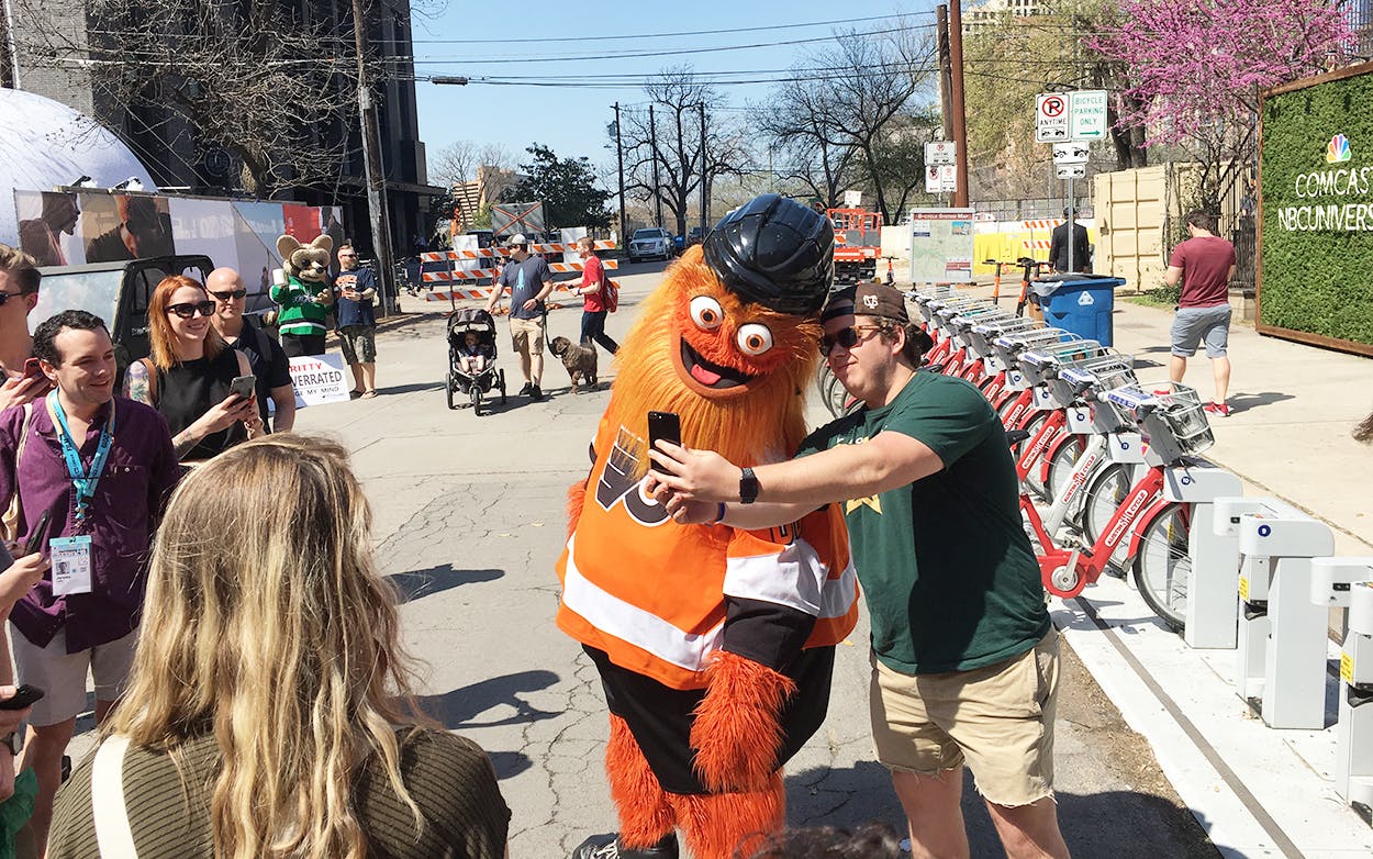 Philadelphia Flyers mascot Gritty posing for photos with fans outside on Rainey Street