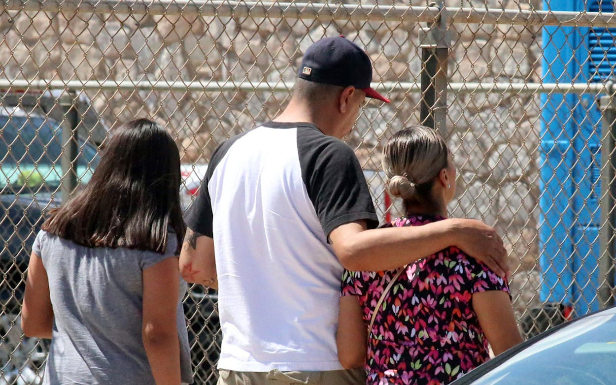 People walk out of an elementary school after family members were asked to reunite following a shooting at a shopping mall in El Paso on Saturday, Aug. 3, 2019.