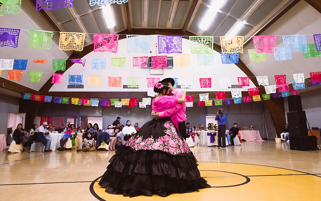 Maya Alvarez and her father dancing at her quinceñera underneath papel picado.