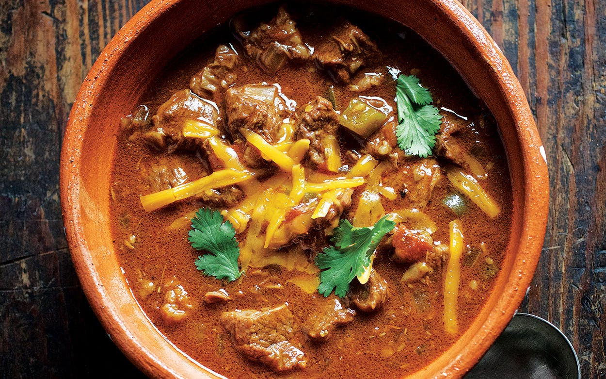 Bowl of Carne Guisada garnished with cheese and cilantro.