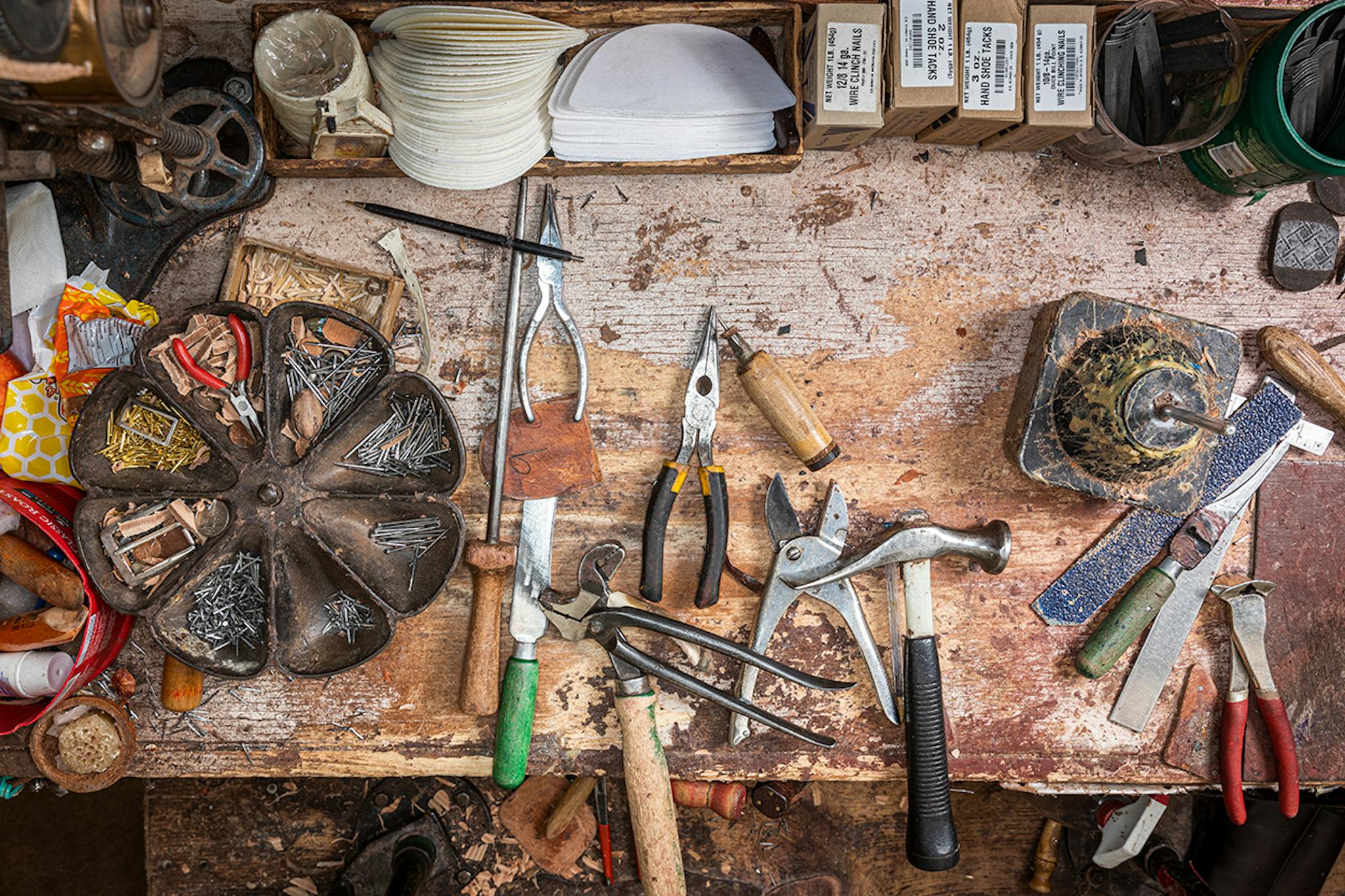 A well-worn work bench with sundry tools of the bootmaking trade.
