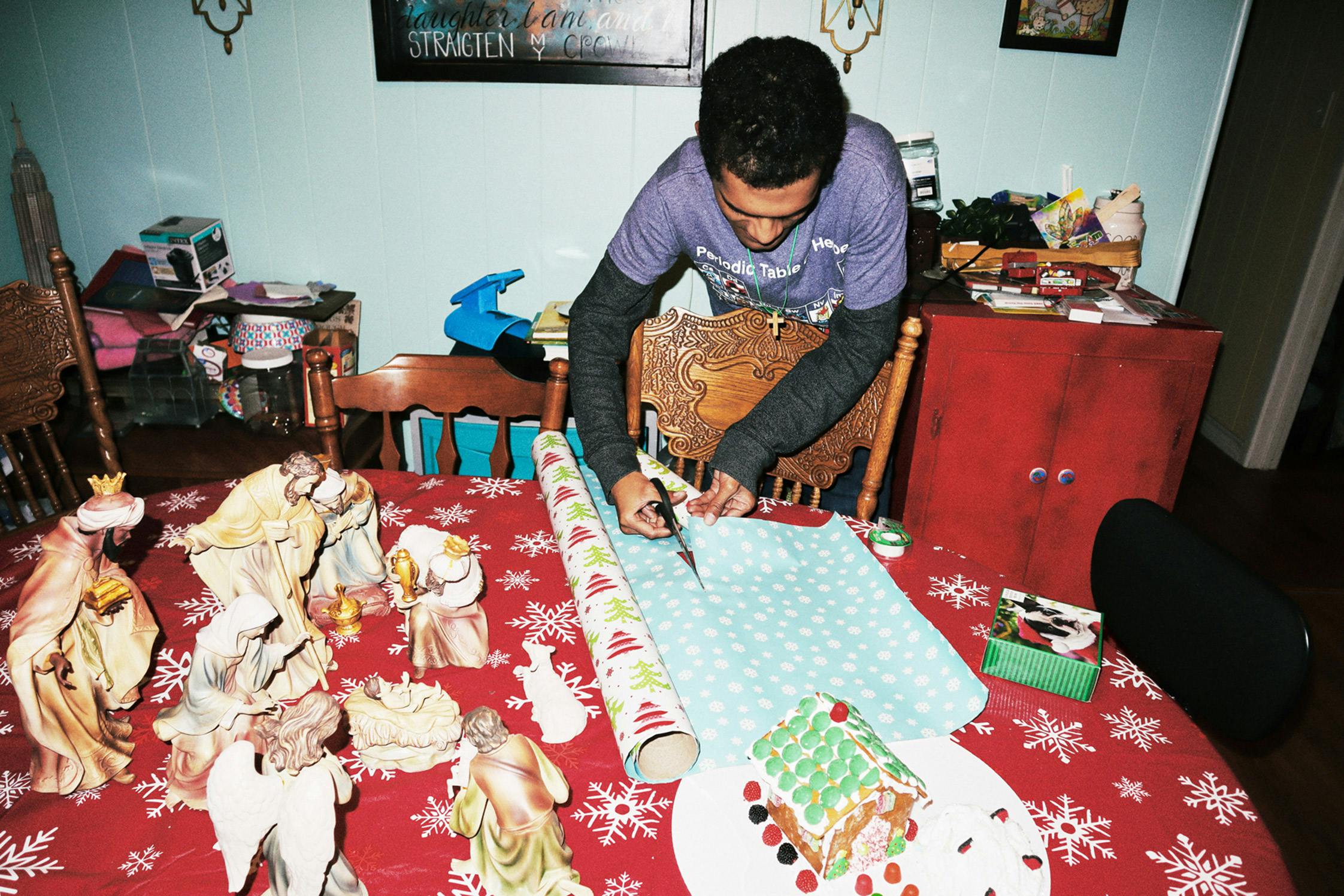 Chris cuts paper to wrap his Christmas gifts with.