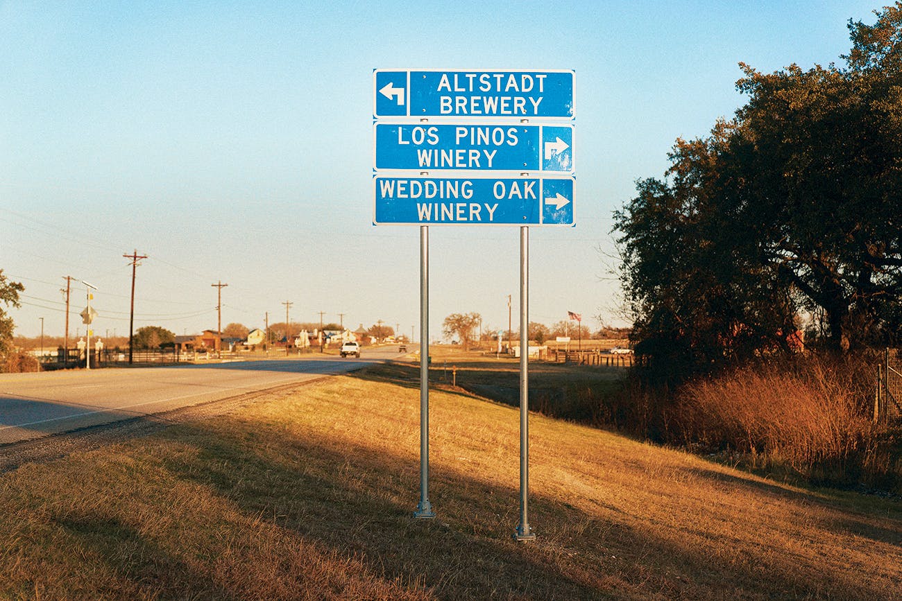 A sign on Highway 290 near Fredericksburg pointing towards Altstadt Brewery, Los Pinos Winery, and Wedding Oak Winery. 