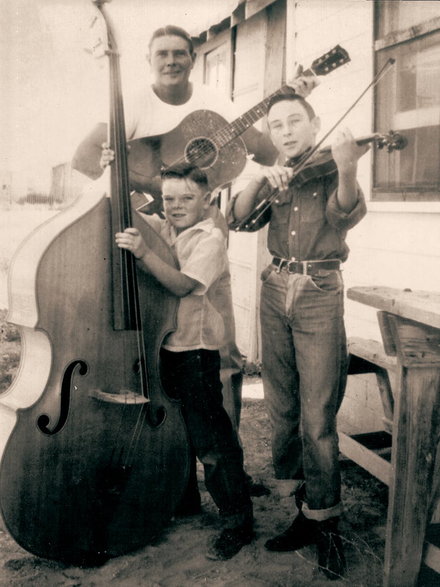 Old photograph of Wayland, Jim, and Dan Seals with different string instruments. 