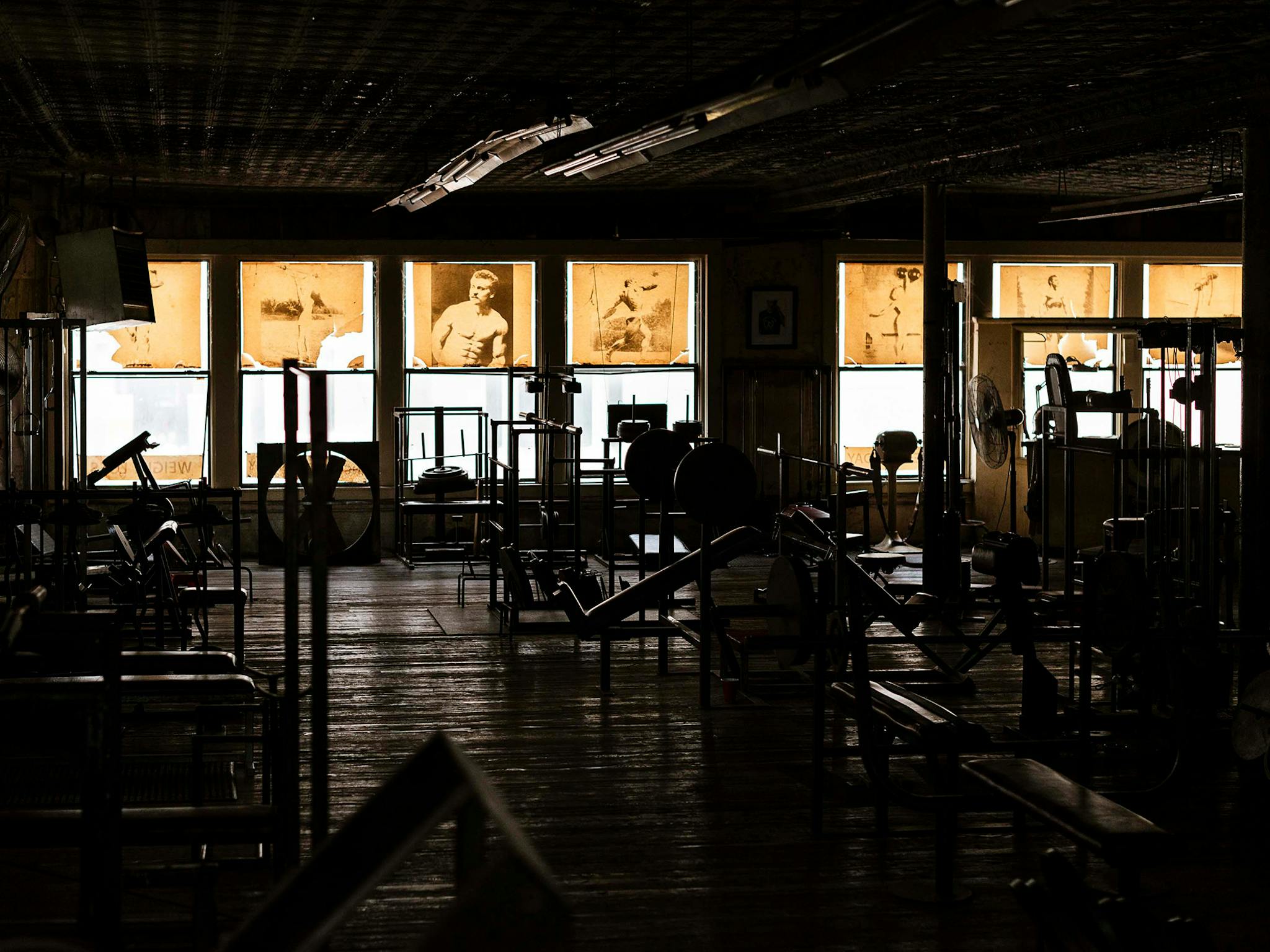 Even during peak times, the gym rarely had more than 15 or 20 people in it, but when it was empty, it took on an entirely different mood. With the fluorescents off and the sun backlighting the yellowed posters that served as window treatments, you can make out the rough flooring (“you wouldn’t walk on that with bare feet,” says Diamond), the almost architectural silhouettes of the equipment, and two fans. Barely visible in the far right window: a vintage vibrating belt once considered a state-of-the-art fat-reducing device.