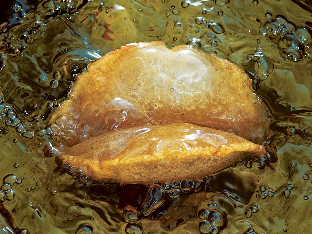 A puffy taco frying in oil.