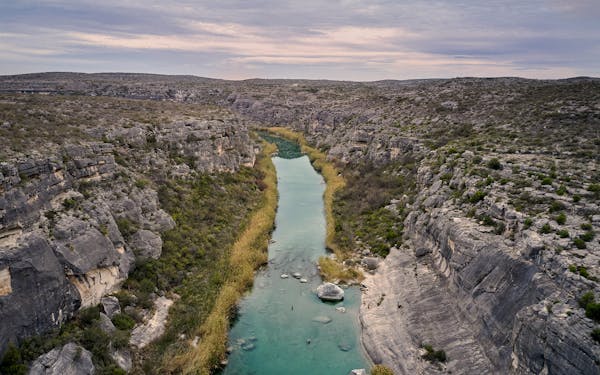 Arial shot of lower pecos river, centered between two cliffs.