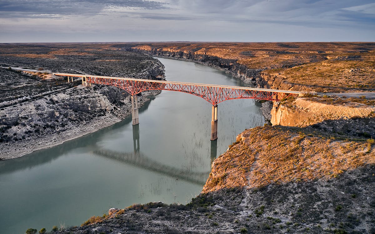 Landscape shot of a bridge stretching over the Pecos River. 